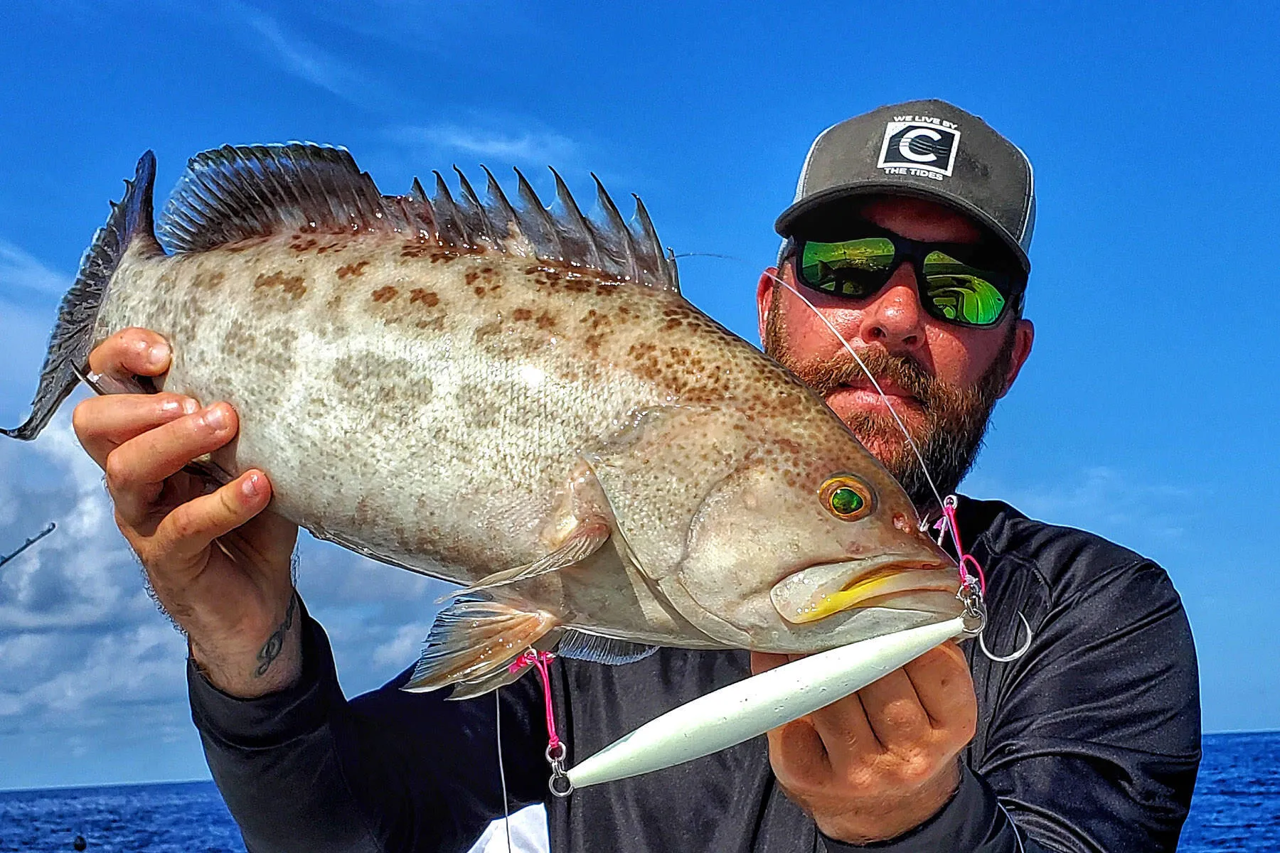 Ryan Hanks holding a grouper caught near a Gulf reef ledge slow pitch jigging