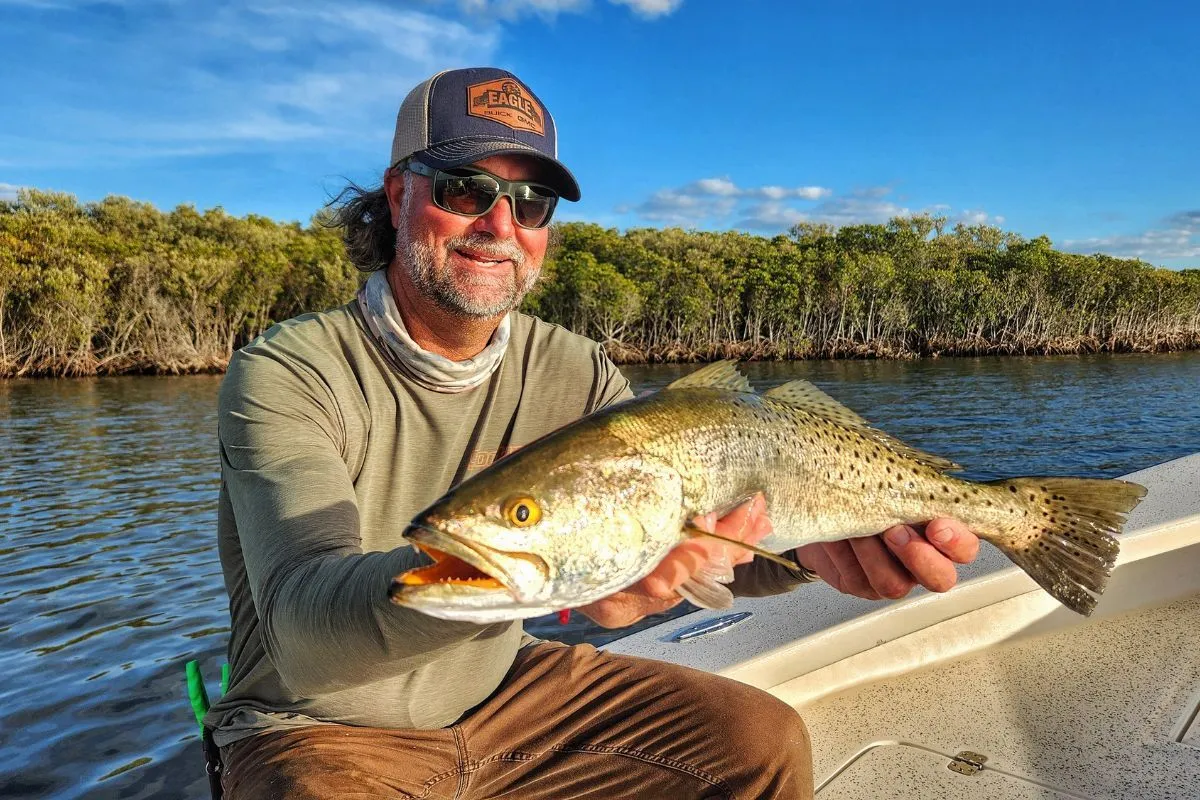 Captain William Toney holding a trophy spotted seatrout on a shallow limestone flat near Homosassa, Florida