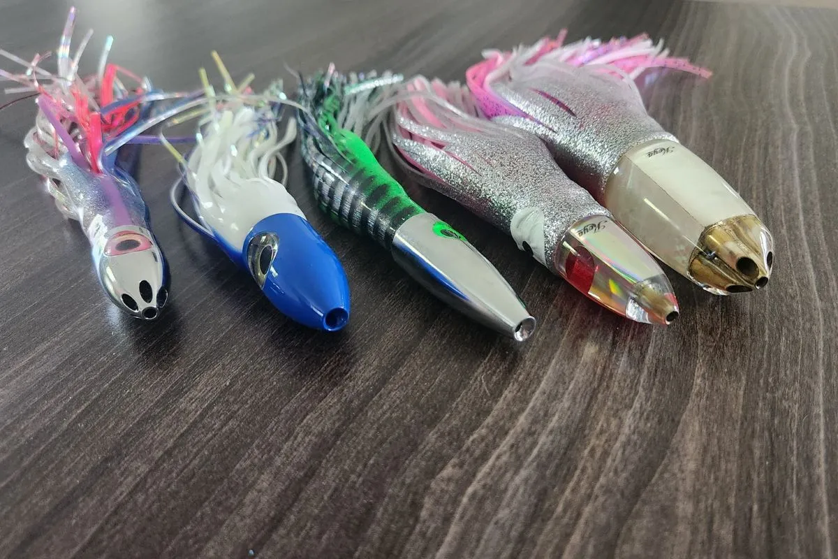 Five skirted bullet head trolling lures in mixed colors laid out for offshore tuna fishing.
