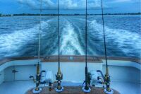 spinning reels and rods in the rocket launcher of sport fishing yacht heading offshore