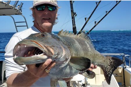 Tom Hilton holding big coral trout caught bottom fishing with soft plastic jig