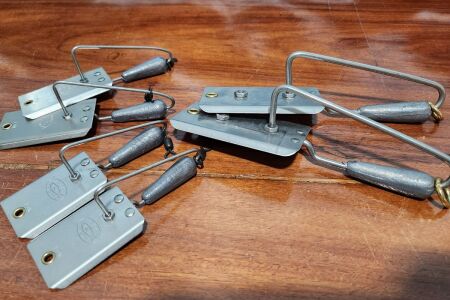 Six trolling planers in three sizes laid out on a boat covering board for kingfish, wahoo, and tuna fishing