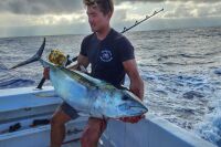Angler holding a yellowfin tuna caught trolling a skirted marlin lure offshore in Kona Hawaii with Shawn Rotella.