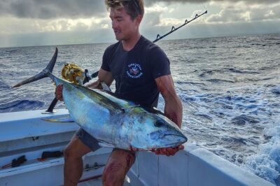 Angler holding a yellowfin tuna caught trolling a skirted marlin lure offshore in Kona Hawaii with Shawn Rotella.
