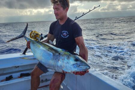 Angler holding a yellowfin tuna caught trolling a skirted marlin lure offshore in Kona Hawaii with Shawn Rotella.