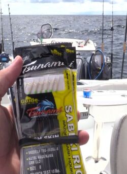 Seth Horne holding the sabiki rigs used to catch hardtails and live bait, with the stern of a Freeman boat behind him.